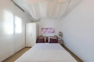 a bedroom with a large white bed with purple pillows at Uno Beachfront Suite in Livadia