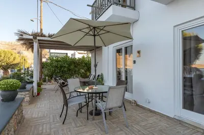 a patio with a table and chairs and an umbrella at Uno Beachfront Suite in Livadia