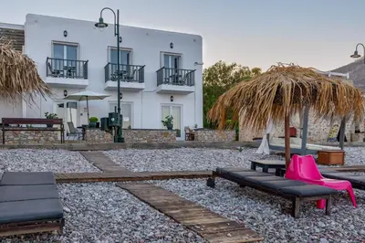 a patio with chairs and an umbrella and a building at Uno Beachfront Suite in Livadia