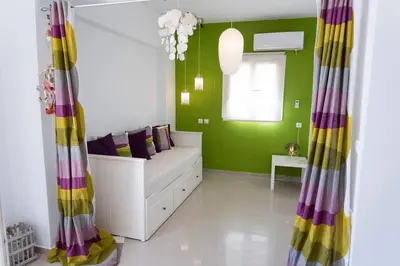 a green room with a white couch and a window at Uno Beachfront Suite in Livadia