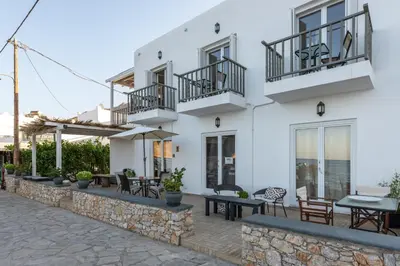 a white building with tables and chairs in front of it at Uno Beachfront Suite in Livadia