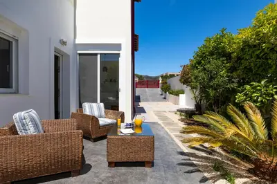 a patio with wicker chairs and a table with drinks on it at ELENA HOUSE 2 in Gennadi