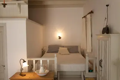 a small bedroom with a bed and a table at Casa Rinio in Symi