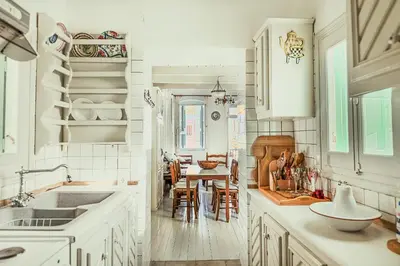 a kitchen with white cabinets and a dining room at Casa Rinio in Symi