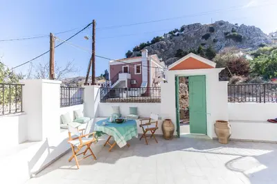 a patio with a table and chairs and a house at Casa Rinio in Symi