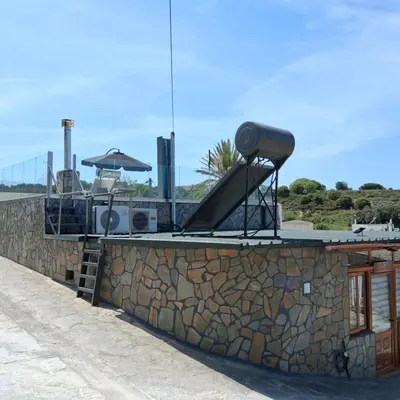 a house with a stone wall and an umbrella at Sioutis House in Soroni