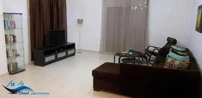 a living room with a couch and a tv at Theti Apartment in Faliraki