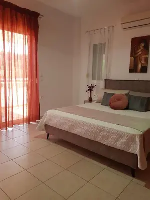 a bedroom with a large bed and a window at Theti Apartment in Faliraki