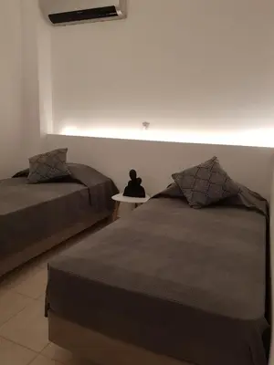 a bedroom with two beds and a small table at Theti Apartment in Faliraki