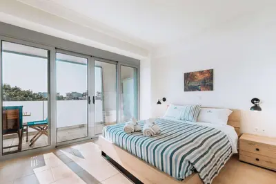 a white bedroom with a bed and a balcony at Rhodes Port Haven Suite in Rhodes Town