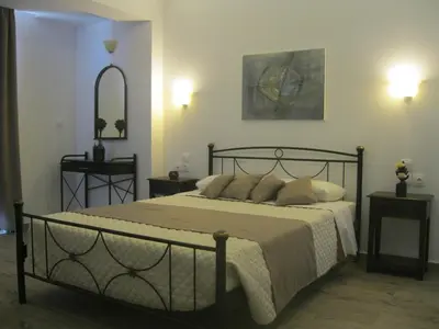 a bedroom with a bed with two tables and a mirror at Seaside Studios Kirania in Kiotari