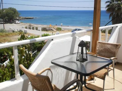 a table on a balcony with a view of the ocean at Seaside Studios Kirania in Kiotari