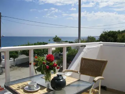 a table with a vase of flowers on a balcony at Seaside Studios Kirania in Kiotari