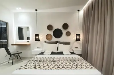 a white bedroom with a bed and a chair at St.Thomas Beach Luxury Apartments in Pefki Rhodes