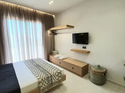 a bedroom with a bed and a flat screen tv at St.Thomas Beach Luxury Apartments in Pefki Rhodes