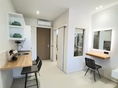 a kitchen with a sink and chairs in a room at St.Thomas Beach Luxury Apartments in Pefki Rhodes