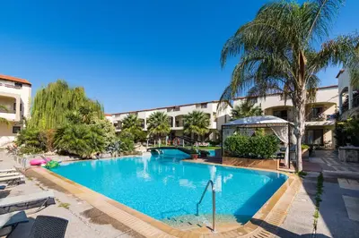a large swimming pool in a resort with palm trees at Villas Duc - Rhodes in Ialyssos