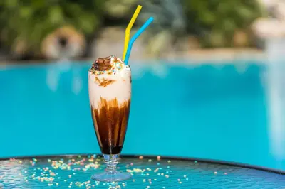 a milkshake sitting on a table next to a pool at Villas Duc - Rhodes in Ialyssos