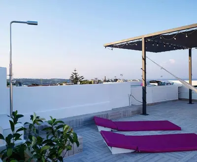 a rooftop patio with purple chairs and an umbrella at KALITHEA-HILLS APARTMENT 3 in Koskinou