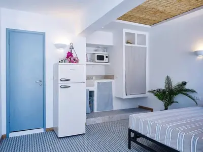 a bedroom with a bed and a kitchen with a microwave at KALITHEA-HILLS APARTMENT 3 in Koskinou