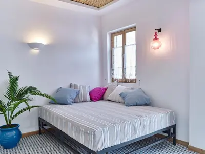 a bed in a white room with a potted plant at KALITHEA-HILLS APARTMENT 3 in Koskinou