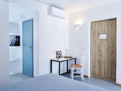 a bedroom with a bed and a desk and a door at KALITHEA-HILLS APARTMENT 3 in Koskinou