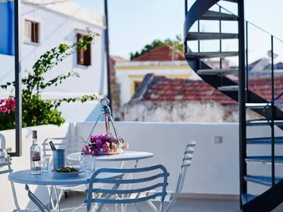 a table and chairs on a patio with a staircase at KALITHEA-HILLS APARTMENT 3 in Koskinou