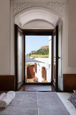 a bedroom with an open door with a view of a house at Lindos Elpis in Líndos