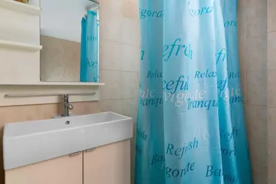 a bathroom with a sink and a blue shower curtain at Lindos Elpis in Líndos