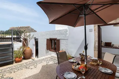 a wooden table with an umbrella on a patio at Lindos Elpis in Líndos