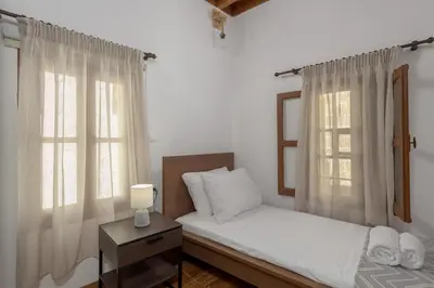 a bedroom with a bed and two windows at RUSTIC SELF-INN in Rhodes Town