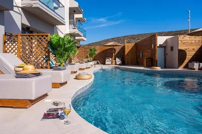 a swimming pool with white furniture and a building at Oasis Hotel Prasonisi in Prasonisi