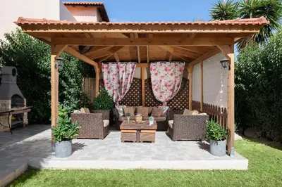 a wooden pergola with a couch and a table at EvMar Villa in Rhodes Town