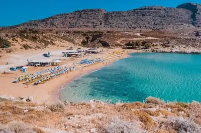 a beach with a bunch of umbrellas and chairs and water at KALITHEA-HILLS VILLA with pool for 8 up to 12 IN RHODES TOWN in Rhodes Town