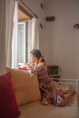 a woman sitting on a couch looking out a window at Anesis Traditional Rhodian House in Kattavía