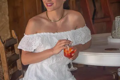 a woman in a white dress holding a drink at Anesis Traditional Rhodian House in Kattavía