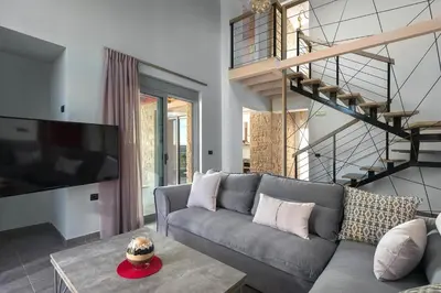a living room with a gray couch and a tv at Luxury villa in Lachania near sea in Lachania