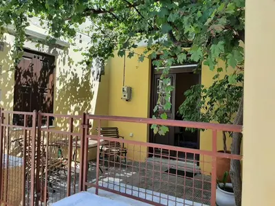 a yellow house with a fence and a tree at Alexandros Traditional House in Ialyssos