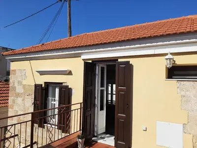 a yellow house with brown doors and a balcony at Alexandros Traditional House in Ialyssos