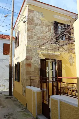a yellow building with a porch and a balcony at Alexandros Traditional House in Ialyssos