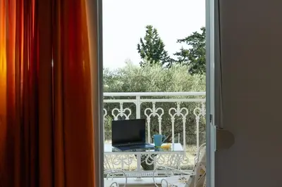 a window with a laptop on a table on a balcony at Villa Chelidonia Afantou in Afantou