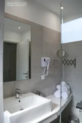 a bathroom with a white sink and a mirror at Haraki Endless Blue Luxury Apartments in Haraki