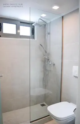 a bathroom with a glass shower with a toilet at Haraki Endless Blue Luxury Apartments in Haraki
