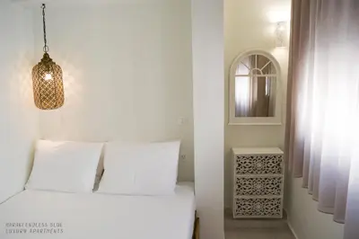 a bedroom with a white bed and a mirror at Haraki Endless Blue Luxury Apartments in Haraki