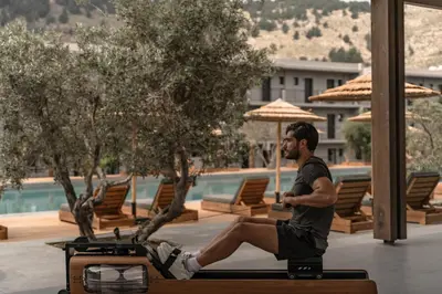 a man sitting on a bench next to a pool at Cook's Club Kolymbia Rhodes -Adults only in Kolimbia