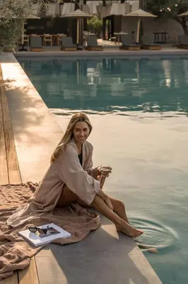 a woman sitting on a towel next to a swimming pool at Cook's Club Kolymbia Rhodes -Adults only in Kolimbia
