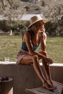 a woman in a hat sitting on a ledge at Cook's Club Kolymbia Rhodes -Adults only in Kolimbia