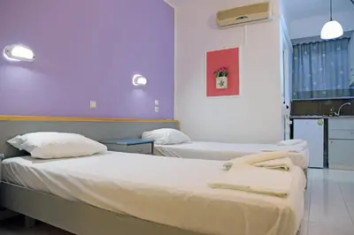 two beds in a room with purple walls at Falirala Central in Faliraki