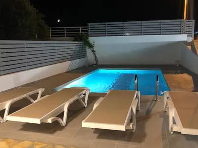 a swimming pool with two loungers next to a house at Casa Greco in Gennadi