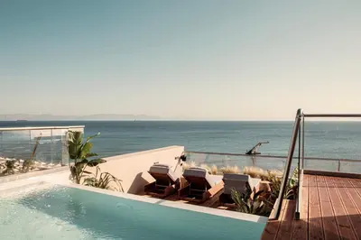 a swimming pool with chairs and a view of the ocean at More Meni City Beach Rhodes in Rhodes Town